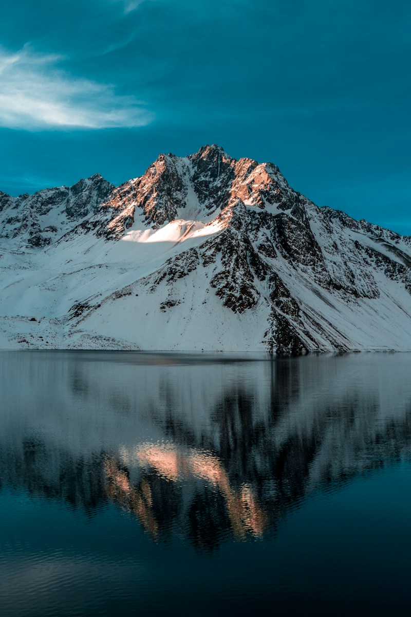 body of water near mountain coated by snow